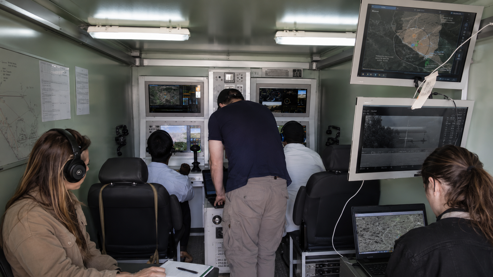 Multi-operator ground control station crew monitoring live UAV feeds